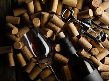 Festive Composition. On Wine Corks Lies A Bottle Of Red Wine, A Corkscrew And A Wine Glass. There Are No People In The Photo. Low Angle View. Wine Collection, Tasting, Wine Cellar.