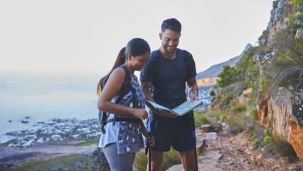 Poster - This is so helpful to plot out our hike path. Shot of a young couple using a guide book to complete a hike in a mountain range.