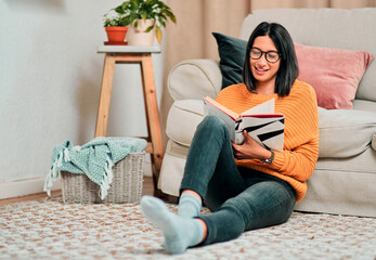 Poster - Nothing says relaxation like reading a good book. Shot of a young woman relaxing on the floor in the living room and reading a book at home.