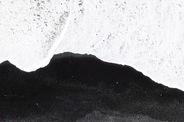 Wall Mural - An aerial view of a black beach in Iceland. Waves and black sand on the beach. View from a drone.