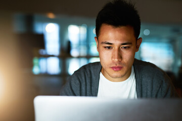 Sticker - His job sometimes requires late nights. Shot of a handsome young male programmer working late in his office.