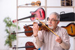 © Elnur - Old male repairman repairing musical instruments at workplace
