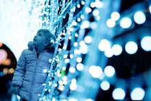 Cute Girl Standing By Illuminated Christmas Lights
