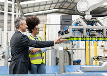 Businessman Discussing With Engineer About Robotic Arm Machine In Factory