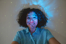 Astro Light Falling On Face Of Happy Woman In Front Of Wall