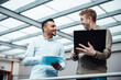 © Westend61 - Smiling businessman holding laptop discussing with colleague at work place