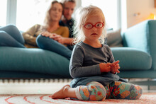 Cute Little Blond Girl Wearing Eyeglasses Sitting In Living Room At Home