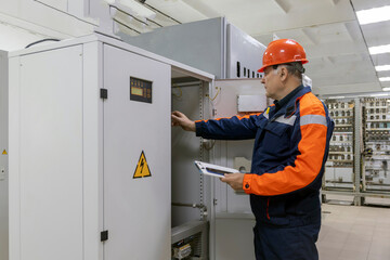 Wall Mural - A man working in the control room. Engineer works and checks the state of electricity distribution in the substation room