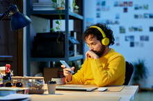 Businessman Listening Music Through Wireless Headphones Using Smart Phone In Office