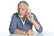 © aletia2011 - Portrait of senior man sitting at table and pointing up with finger