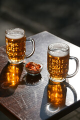 Wall Mural - Two cold draught blonde beers and some peanuts on a table. Drinking on a pub terrace with friends. Drinks and beer photography.