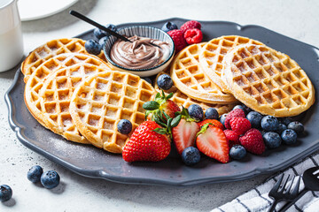 Poster - Homemade waffles with berries and chocolate cream on dark plate, gray background. Family breakfast concept.