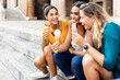 © Xavier Lorenzo - Three pretty multiracial happy women having conversation and eating ice cream outdoor while sitting at the stairs - Friendship and summer vacation on Italy concept - Focus on asian woman