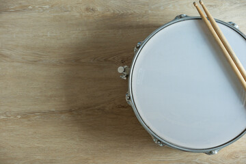 Wall Mural - Drum stick and drum on wooden table background, top view, music concept