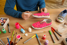 Man Painting On Sneaker At Wooden Table Indoors, Closeup. Customized Shoes