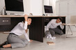 © New Africa - Scared employees hiding under office desks during earthquake