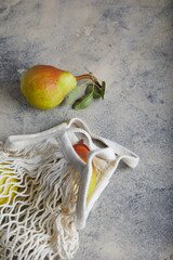 Wall Mural - pears in a knitted white bag on gray with navy cement background, ceramic. place for text.