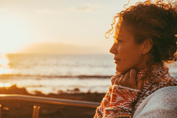 enjoyed and serene lady dreaming and thinking outdoor with ocean beach and sunset light in backgroun