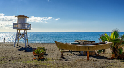 Panoramic view of the Mediterranean beach of Cala del Moral, Malaga, with lifeguard tower and boat ashore.