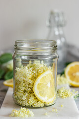 Wall Mural - Homemade elderflower syrup with lemons and freshly picked elderflowers. The flowers are edible and can be used to add flavour and aroma to both drinks and desserts.