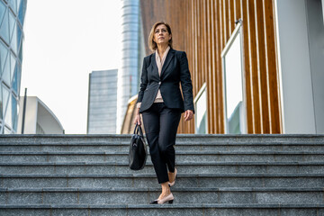 beautiful mature adult business woman in a suit walking in the finance district, confident and professional female lawyer going to the court of justice, resolution mood