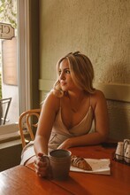 Blonde Woman In Light Top Sitting At Table In A Restaurant