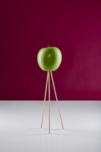 Green Apple On A Stand Against Pink Wall