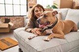Fototapeta Zwierzęta - Young caucasian woman smiling confident lying on sofa with dog at new home