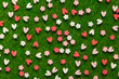 Confetti in the shape of hearts and floral red and pink on the background of an artificial lawn. Macro idea for Valentine's Day