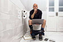 Mature Man Working Online While Using The Bathroom