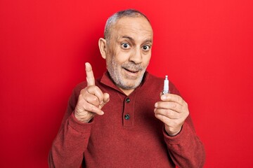 Canvas Print - Handsome mature man holding spark plug surprised with an idea or question pointing finger with happy face, number one