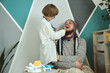 Father and child playing clinic and doctor, little boy dentist in medical gown with stethoscope treats dad