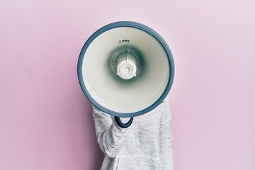 Wall Mural - Young brunette woman shouting and screaming through megaphone over pink isolated background