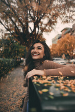 Smiling Woman In Brown Shirt Standing Near Autumn Tree Leaves
