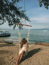 Woman Sitting On Swing Chair Near Sea