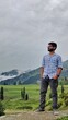 © Scopio - Young South Asian man standing on green grass field