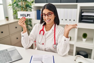 Canvas Print - Young hispanic doctor woman holding help banner celebrating achievement with happy smile and winner expression with raised hand