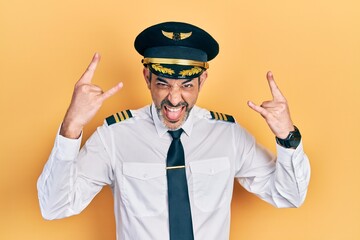 Poster - Handsome middle age man with grey hair wearing airplane pilot uniform shouting with crazy expression doing rock symbol with hands up. music star. heavy music concept.