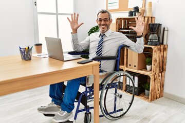 Sticker - Middle age hispanic man working at the office sitting on wheelchair showing and pointing up with fingers number nine while smiling confident and happy.