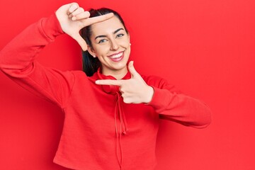 Canvas Print - Beautiful woman with blue eyes wearing gym clothes and headphones smiling making frame with hands and fingers with happy face. creativity and photography concept.