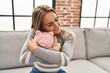 Young blonde woman smiling confident hugging piggy bank at home