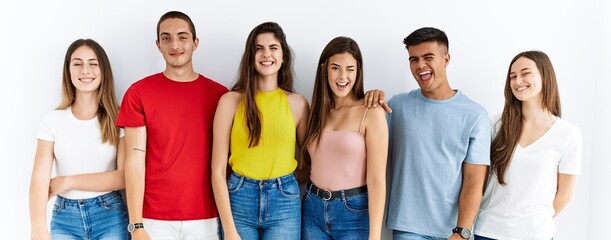 Canvas Print - Group of people wearing casual clothes standing over isolated background winking looking at the camera with sexy expression, cheerful and happy face.