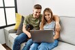 © Krakenimages.com - Young hispanic couple smiling happy using laptop sitting on the sofa  with dog at home.