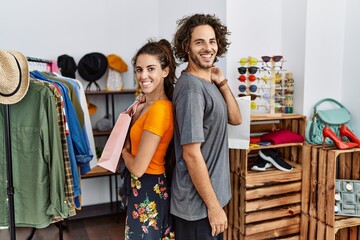 Sticker - Young hispanic couple holding shopping bags at retail shop looking to side, relax profile pose with natural face and confident smile.