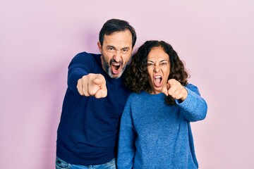 Poster - Middle age couple of hispanic woman and man hugging and standing together pointing displeased and frustrated to the camera, angry and furious with you