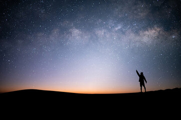 Wall Mural - Young traveler with backpack standing and open arms and watched night sky view, star and milky way alone on top of the mountain. He enjoyed traveling and was successful when he reached the summit.