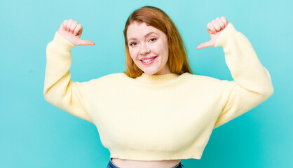 pretty red head woman feeling proud, arrogant and confident, looking satisfied and successful, pointing to self