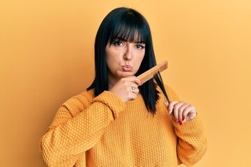 Poster - Young hispanic woman styling hair using comb depressed and worry for distress, crying angry and afraid. sad expression.