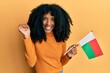 © Krakenimages.com - African american woman with afro hair holding madagascar flag screaming proud, celebrating victory and success very excited with raised arm