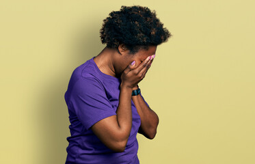 Wall Mural - African american woman with afro hair wearing casual purple t shirt with sad expression covering face with hands while crying. depression concept.